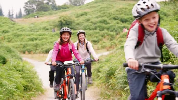 年轻的家庭在露营假期骑山地自行车玩得开心，特写，前视图，湖区，英国
