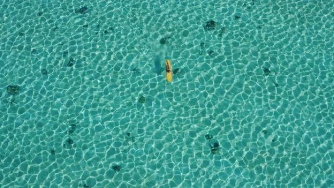 女人在黄色冲浪板上划水的鸟瞰图