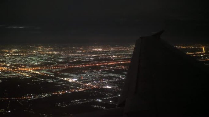 飞机在夜间飞越城市，空中飞机窗口视图