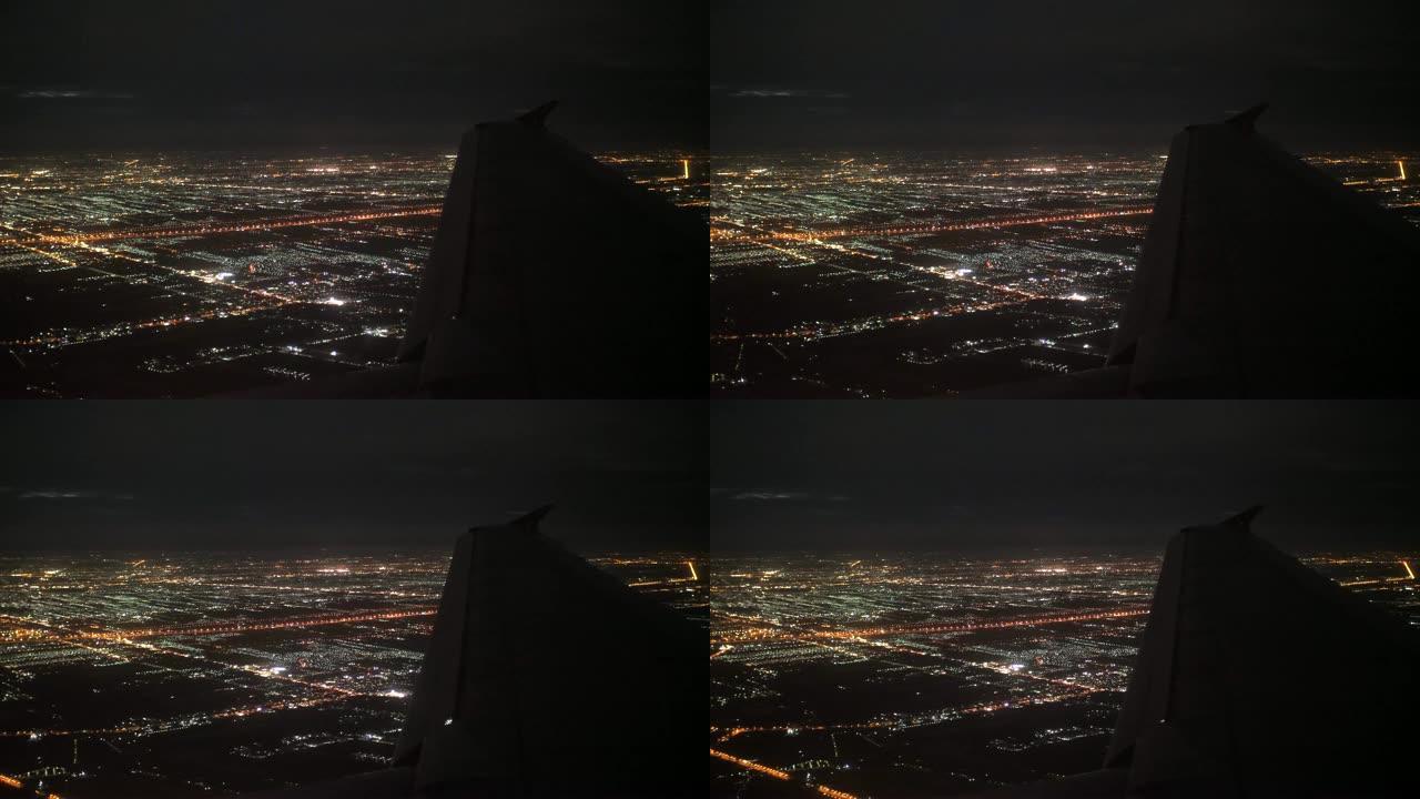 飞机在夜间飞越城市，空中飞机窗口视图