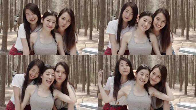 十几岁的女性快乐地对着镜头微笑，一群年轻的亚洲朋友在森林里露营或野餐。妇女在夏季进行冒险活动并在假期