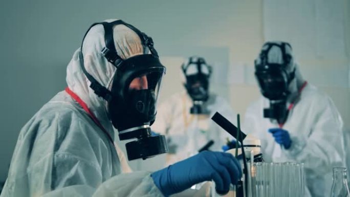 在COVID-19、冠状病毒抗体研究期间，身着防护服的实验室工作人员正在使用显微镜。
