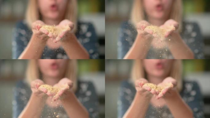 慢动作: 年轻的厨师举起一把玉米面，对着镜头吹。
