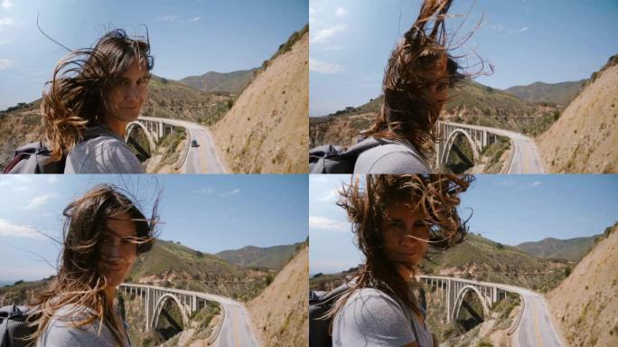 美丽快乐的年轻女子，头发飞扬，微笑着，在大苏尔比克斯比大桥的观察点对着镜头摆姿势。
