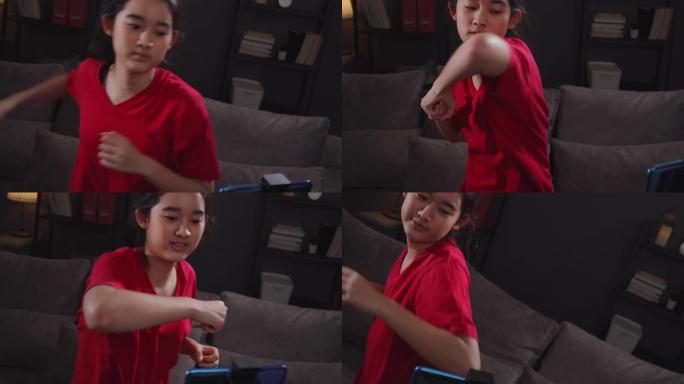 迷人的亚洲少年在家里的客厅在她的智能手机中观看和做拳击在线直播课。她在应用程序中使用手机进行训练练习