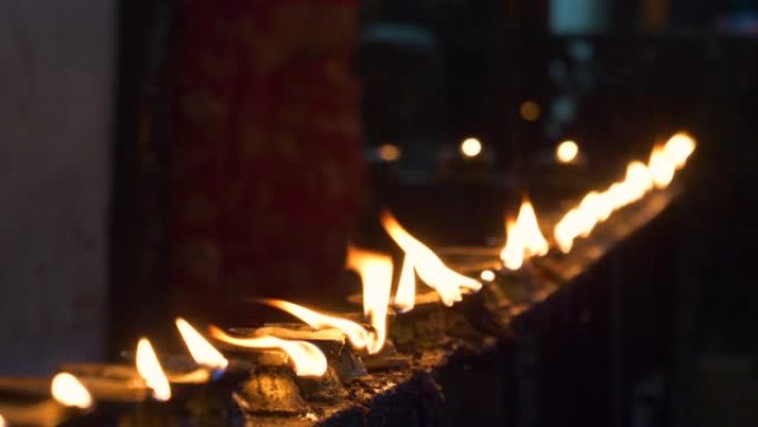 特写: 佛教从业者在寺庙内点燃小油烛。