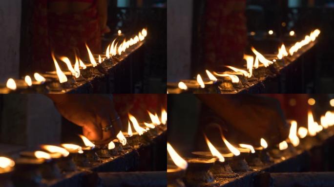 特写: 佛教从业者在寺庙内点燃小油烛。