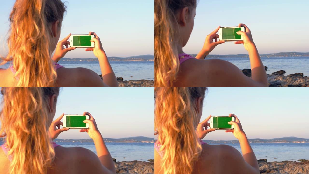 经过岩石海岸训练。女孩用绿屏检查她的智能手机