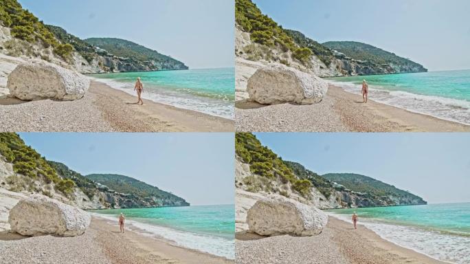 WS妇女沿着意大利普利亚阳光明媚的绿松石海行走
