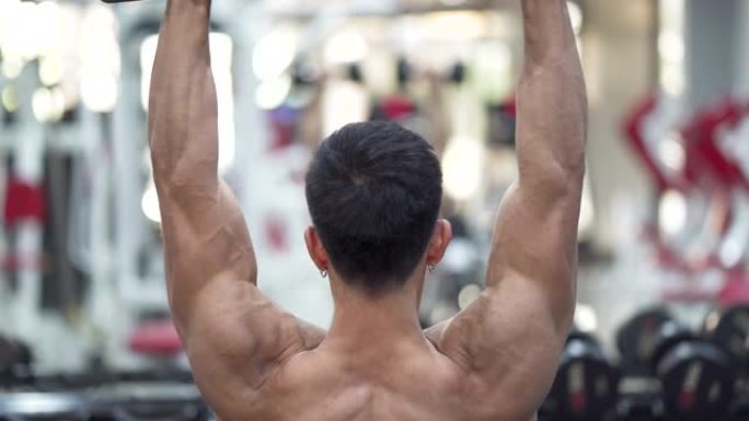 亚洲年轻人在健身房锻炼手臂和肩膀后视图。