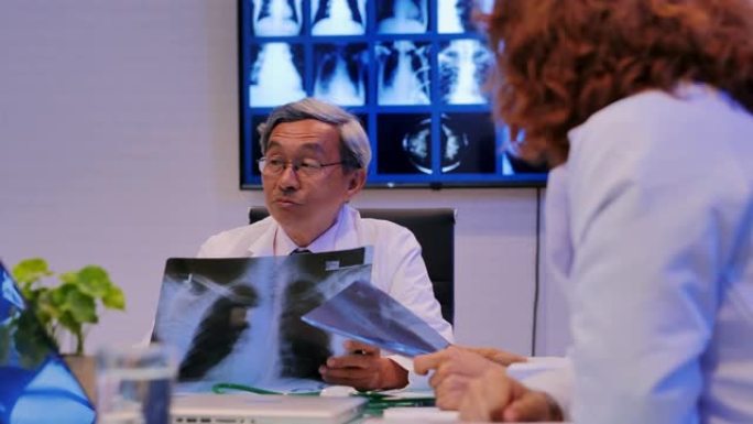 在骨骼研究实验室会见医学科学家团队的高科技讨论周围有显示CT，MRI扫描的监视器。医疗保健，医学教育