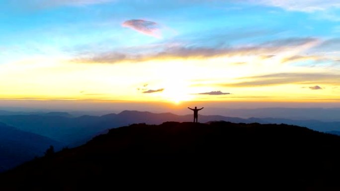 夕阳背景上站在山上的快乐男