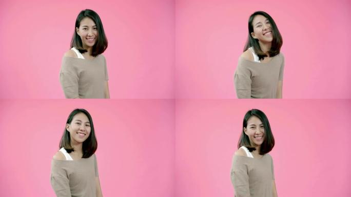 微笑着可爱的亚洲女性，表情积极，笑容灿烂，穿着休闲服装，看着粉红色背景的相机。快乐可爱的快乐女人快乐