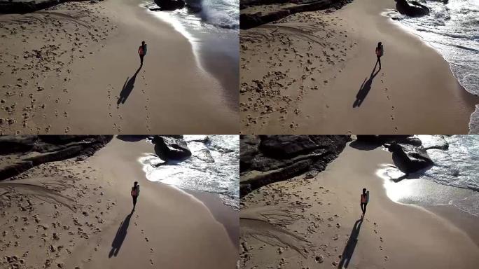 美丽的女人赤脚走在沙滩上，背着她的瑜伽垫