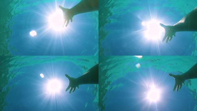 POV: 溺水的女孩伸向刺眼的阳光和宁静的海洋表面。