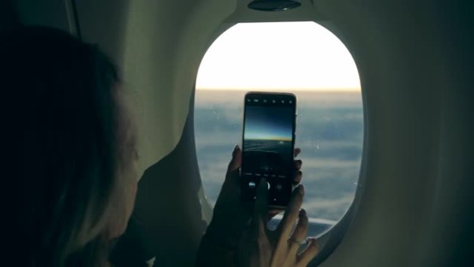 在飞机上拍照时，女人手中的手机