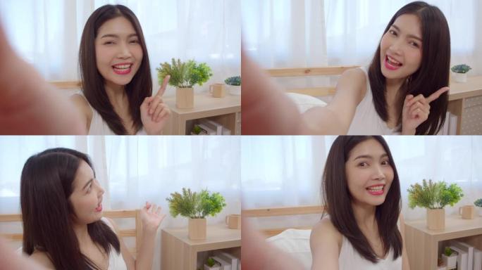 年轻的亚洲青少年妇女在家中vlog，女性使用智能手机在卧室的社交媒体上制作vlog视频。生活方式女人