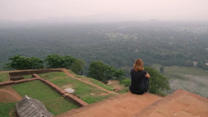 WS女人坐在山顶的废墟上，看着风景秀丽的风景，斯里兰卡