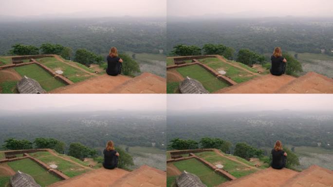 WS女人坐在山顶的废墟上，看着风景秀丽的风景，斯里兰卡