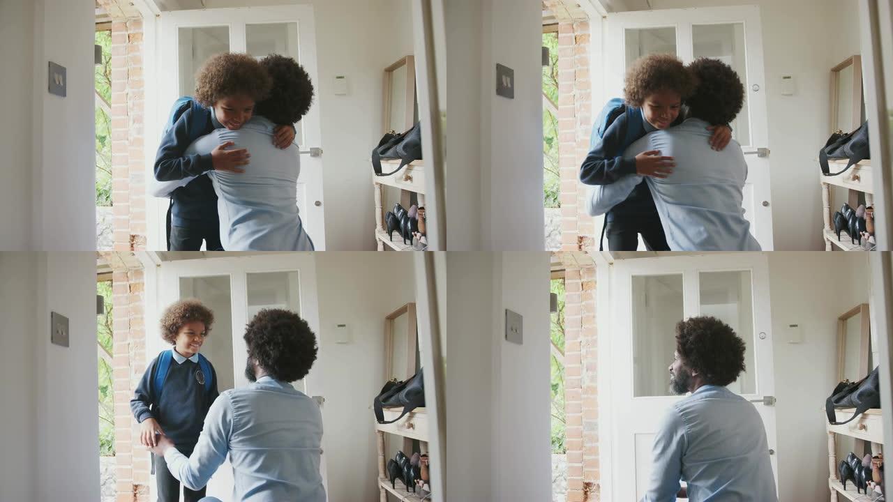 穿着时髦的中年黑人男子跪在前门的走廊上拥抱并告别儿子，然后他早上去上学，角度低