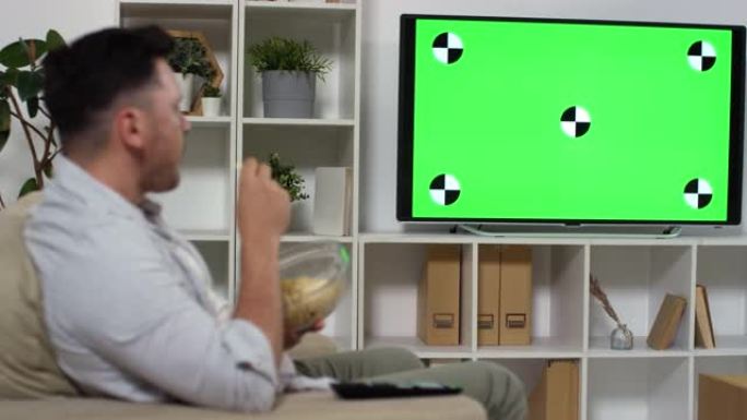 男人吃薯条，看绿色模拟屏幕电视