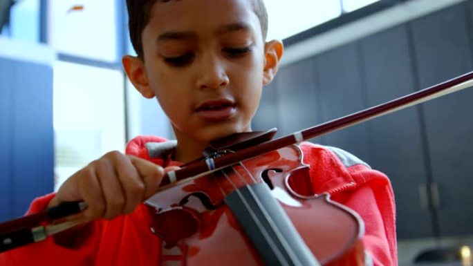 细心的亚洲男生在学校4k教室拉小提琴的前视图
