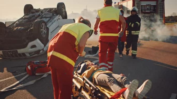 在车祸交通事故现场: 医护人员挽救了一个躺在担架上的小女孩的生命，她得到了急救帮助。消防员带领母亲成