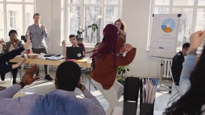 快乐的黑人女公司经理做有趣的疯狂的胜利庆祝舞蹈在现代时尚的办公室。