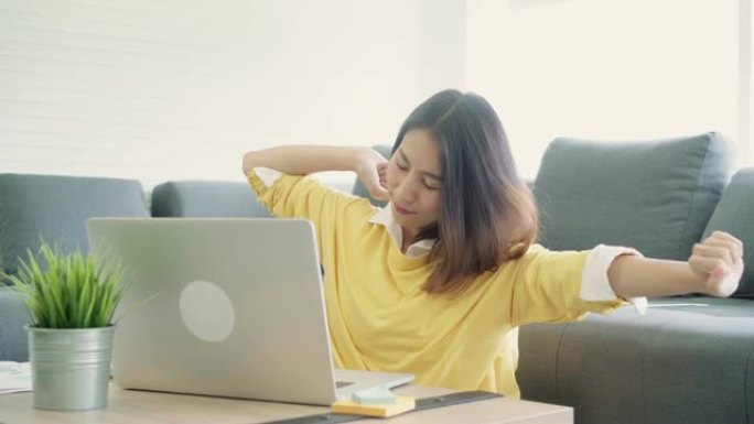商业自由女性伸展身体是因为在笔记本电脑上工作后感到疲倦，聪明的女性在家工作。生活方式女性在家工作后放