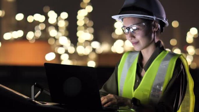 女性亚洲工程师晚上在石油工业工厂使用笔记本电脑进行工程师工作，工程师工作