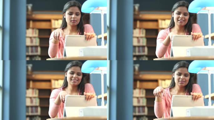 使用数字平板电脑在图书馆中的年轻西班牙裔妇女