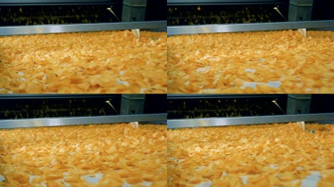 许多油炸薯片在食品生产设施的自动输送机上移动。