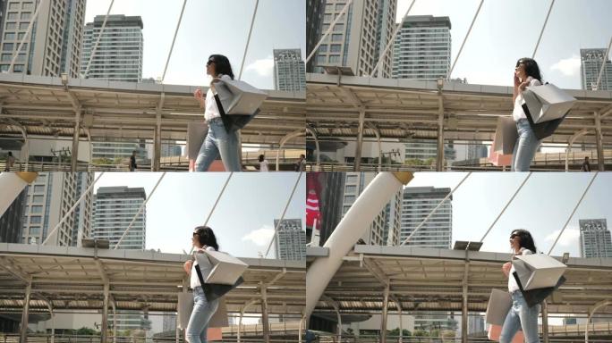 亚洲妇女在城市中带着购物袋散步
