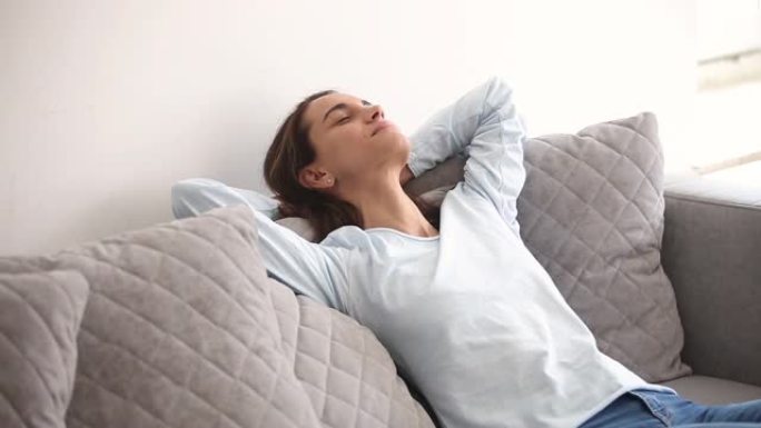 千禧一代的女人闭着眼睛躺在家里舒适的沙发上