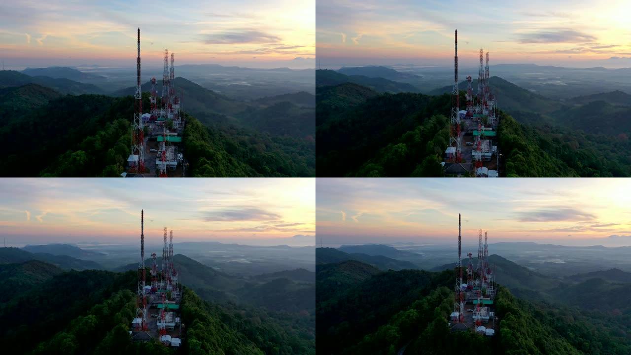 城市上空山上日出时电信桅杆电视天线的鸟瞰图