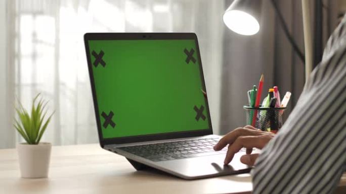 男人在家里的桌子上使用笔记本电脑的绿屏