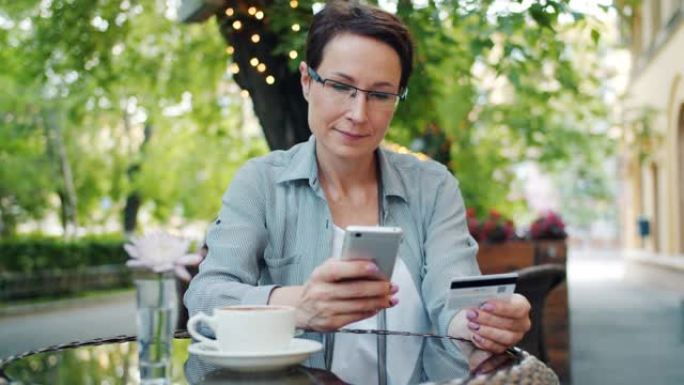 在街头咖啡馆使用智能手机用信用卡付款的女士慢动作