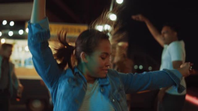 一群朋友正在街头食品汉堡咖啡馆外面举行聚会。一个年轻美女随着音乐跳舞的肖像。今天是现代社区的夜晚。每