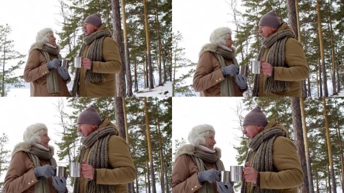 老年夫妇在冬季散步时聊天和喝热茶