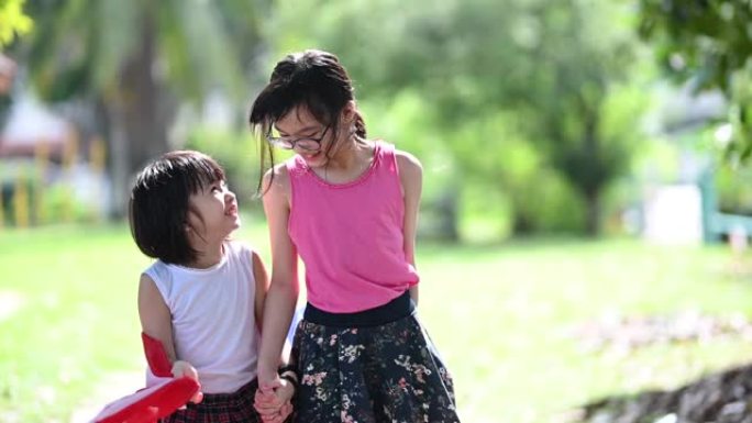 两个亚洲中国小女孩在公园玩，花时间与马来西亚国旗包装