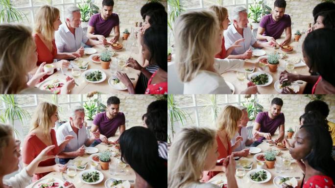 一个多种族的混合年龄的成年朋友在一家小餐馆里共进午餐时一起吃西班牙小吃，高景