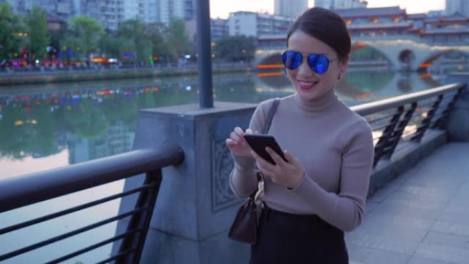 漂亮的亚洲女人使用手机在城市里散步