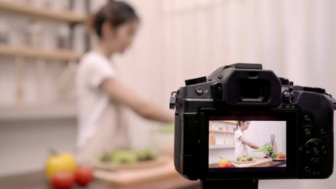 博主亚洲妇女使用相机记录如何制作沙拉健康的食物视频为她的订户，女性使用有机蔬菜准备沙拉适合身体在家里
