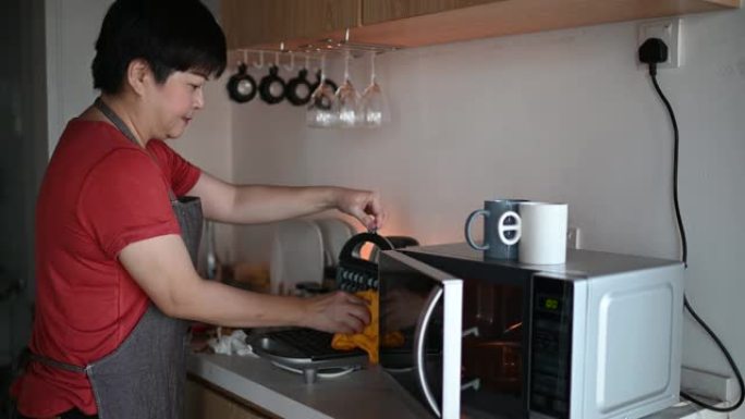 一名亚洲华裔妇女早上在厨房为家人准备早餐华夫饼