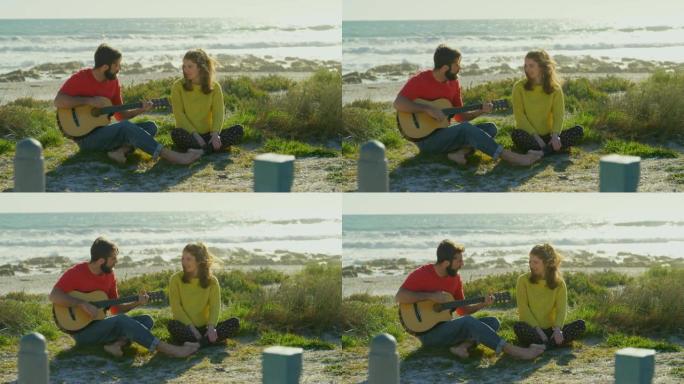 在阳光明媚的日子里，男人在海滩附近为女人弹吉他4k