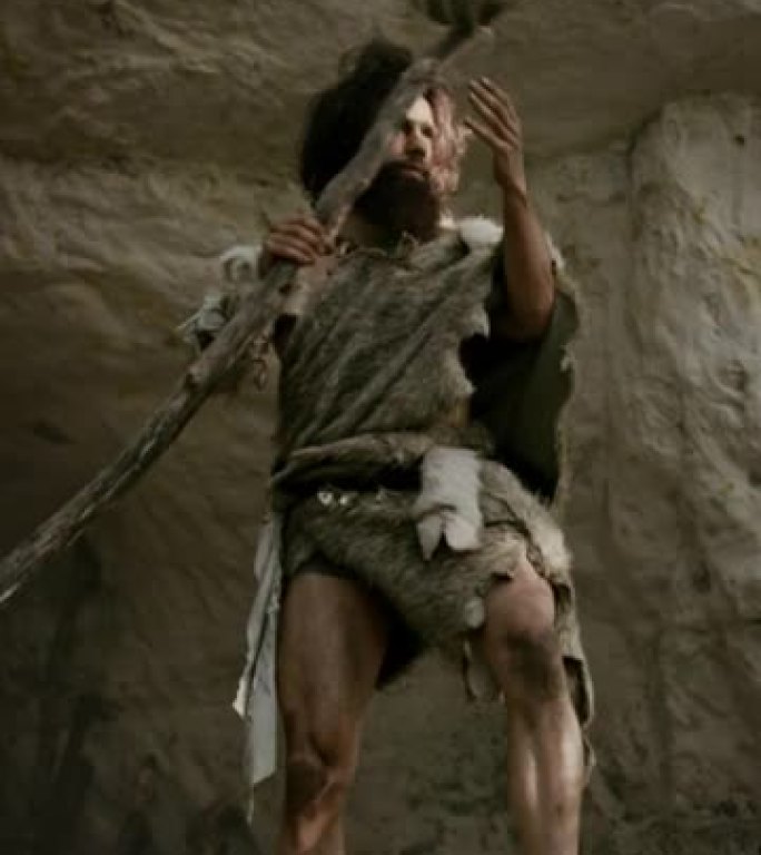 原始穴居人在史前洞穴中穿着动物皮和毛皮，用石尖矛狩猎。史前尼安德特人猎人拾荒。垂直屏幕方向9:16的