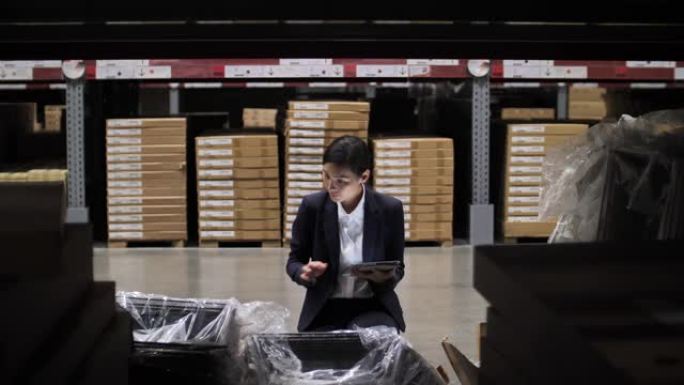 亚洲女商人使用数字平板电脑检查仓库中的产品库存