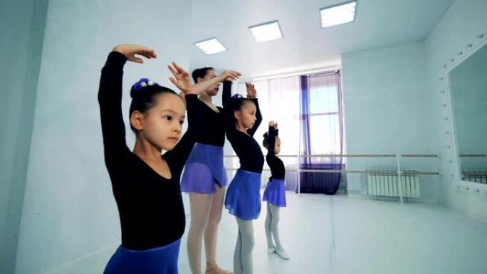 女孩们正在和一位女教练练习芭蕾舞姿势