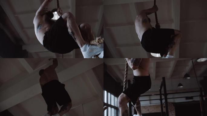 年轻肌肉发达的白人男子爬绳，在大型健身房慢动作中进行核心功能锻炼训练
