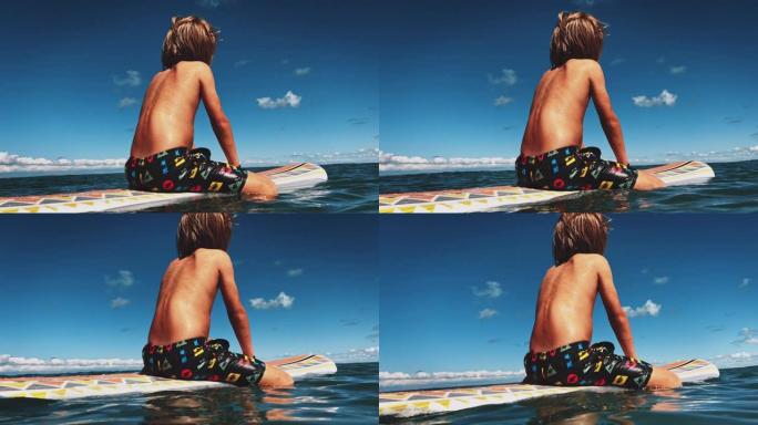 赤膊男孩坐在水中的冲浪板上